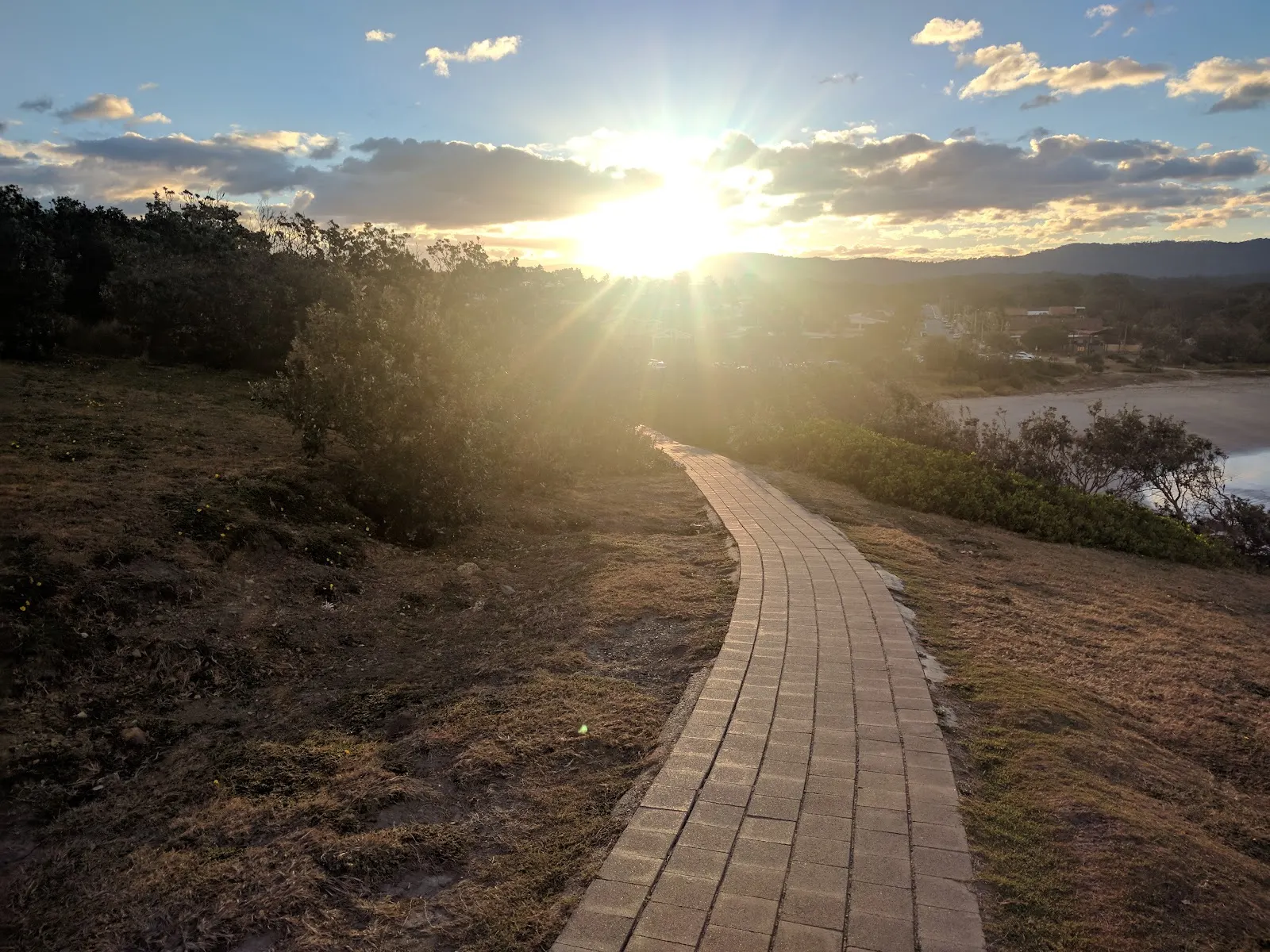 A winding boardwalk through coastal scrub at sunset in Sandy Beach