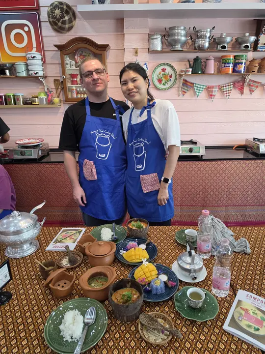 Jeremy and his travel companion in blue aprons behind the dishes they cooked