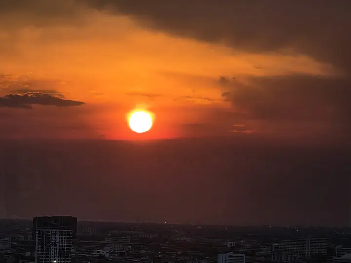 An orange sun setting over Bangkok