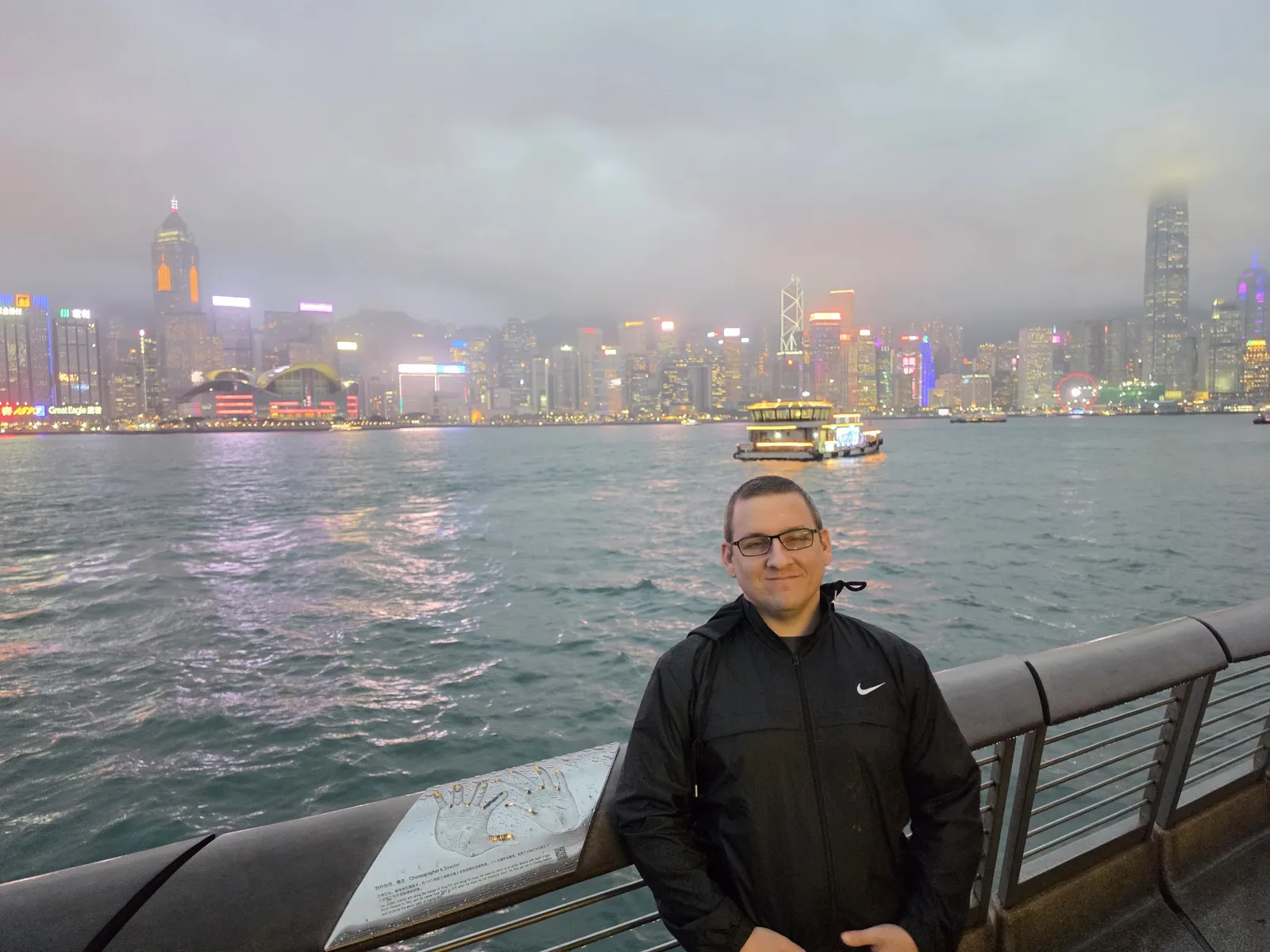Jeremy on the Tsim Sha Tsui waterfront at dusk with the island skyline behind