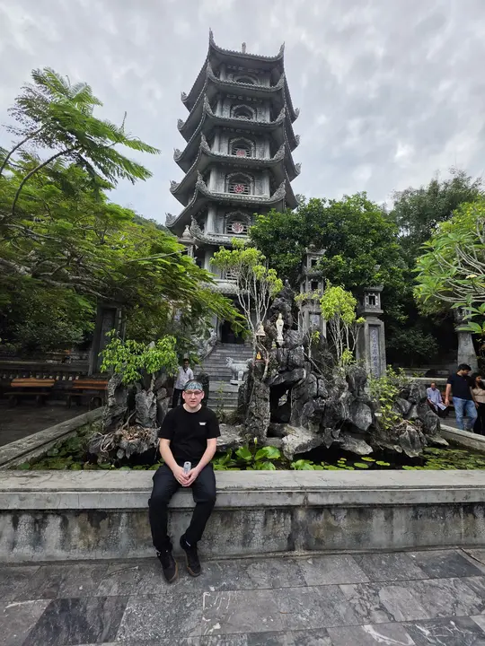 Jeremy sitting on a stone wall in front of the pagoda